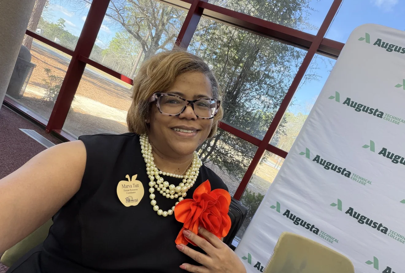 Dr. Tutt in a black dress with pearls and a red flower at Augusta Technical College